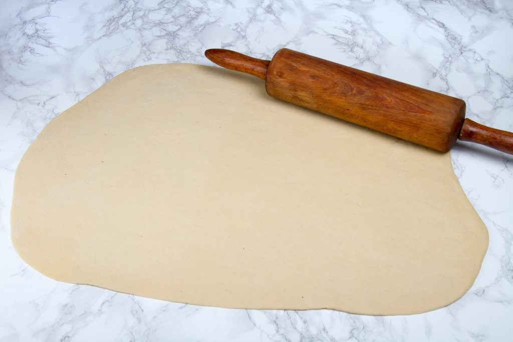 flatten the dough ball with a rolling pin