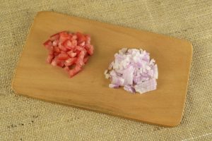 chopped tomatoes and onions on cutting board