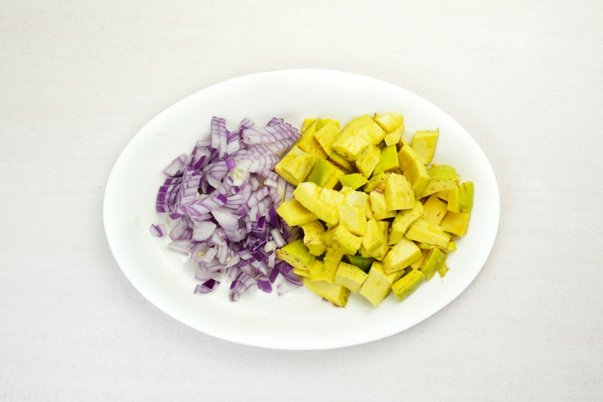 Chopped avocado and red onion on white plate.