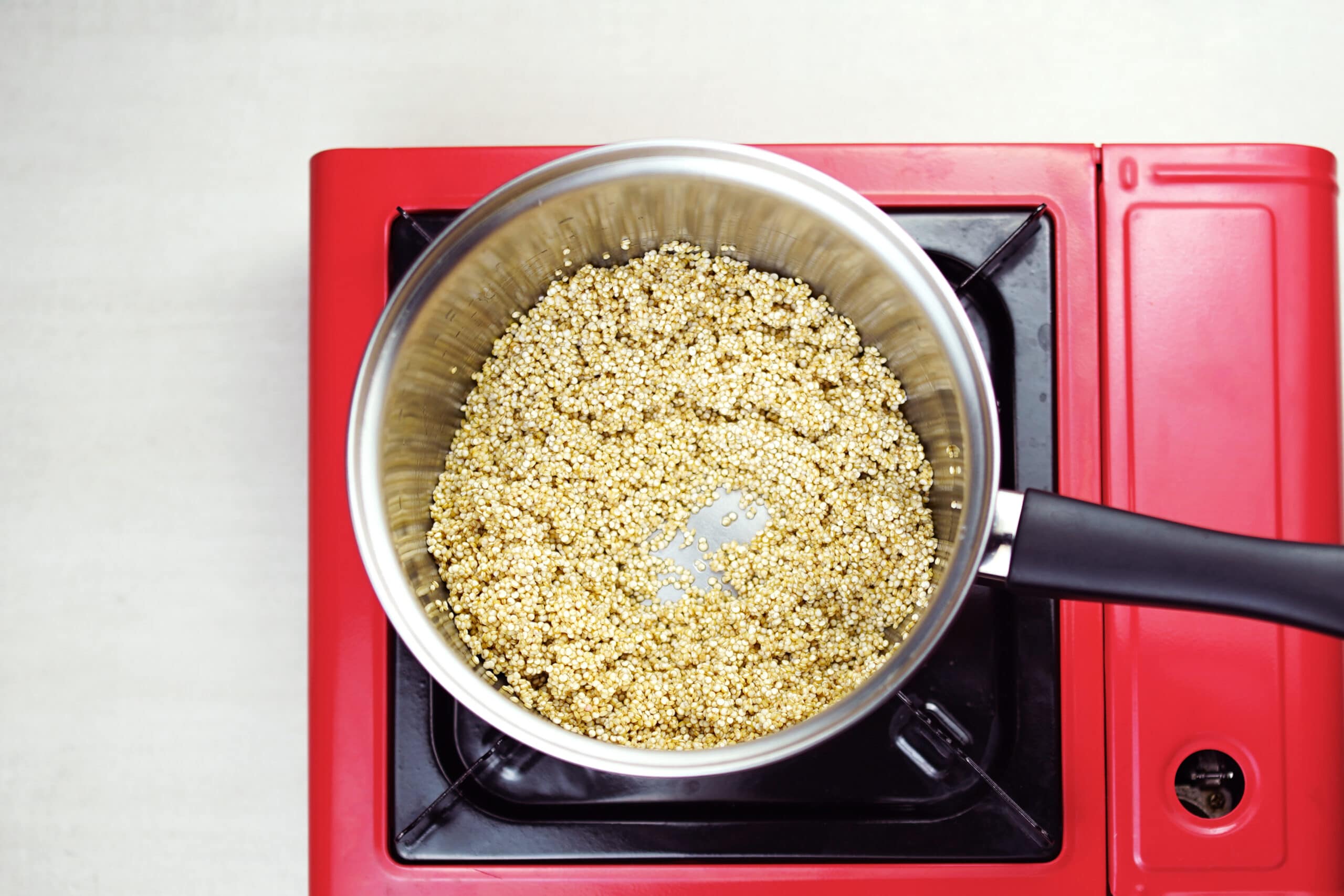 Quinoa in pot on red stove top.