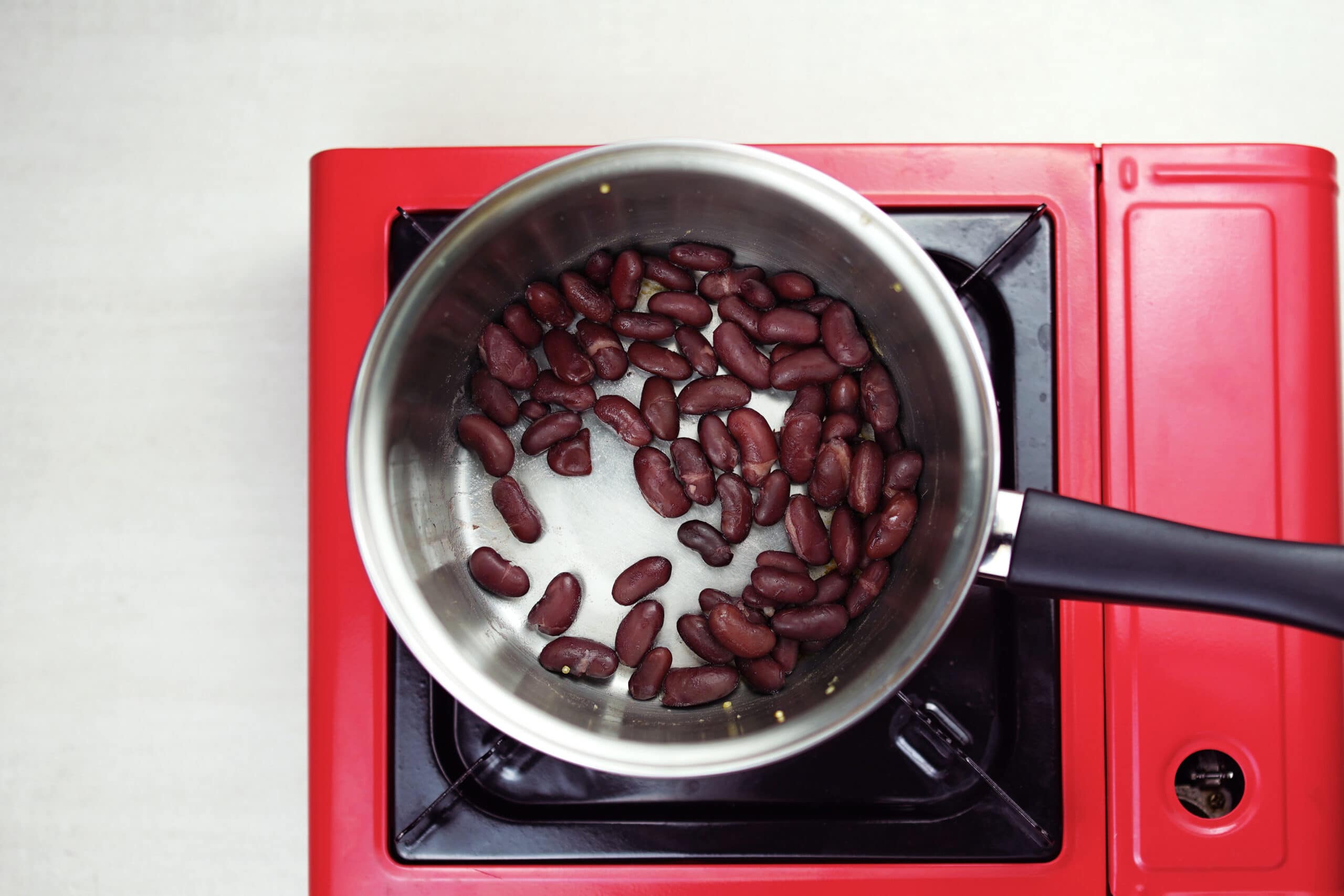 Kidney beans cooking on red stove top.
