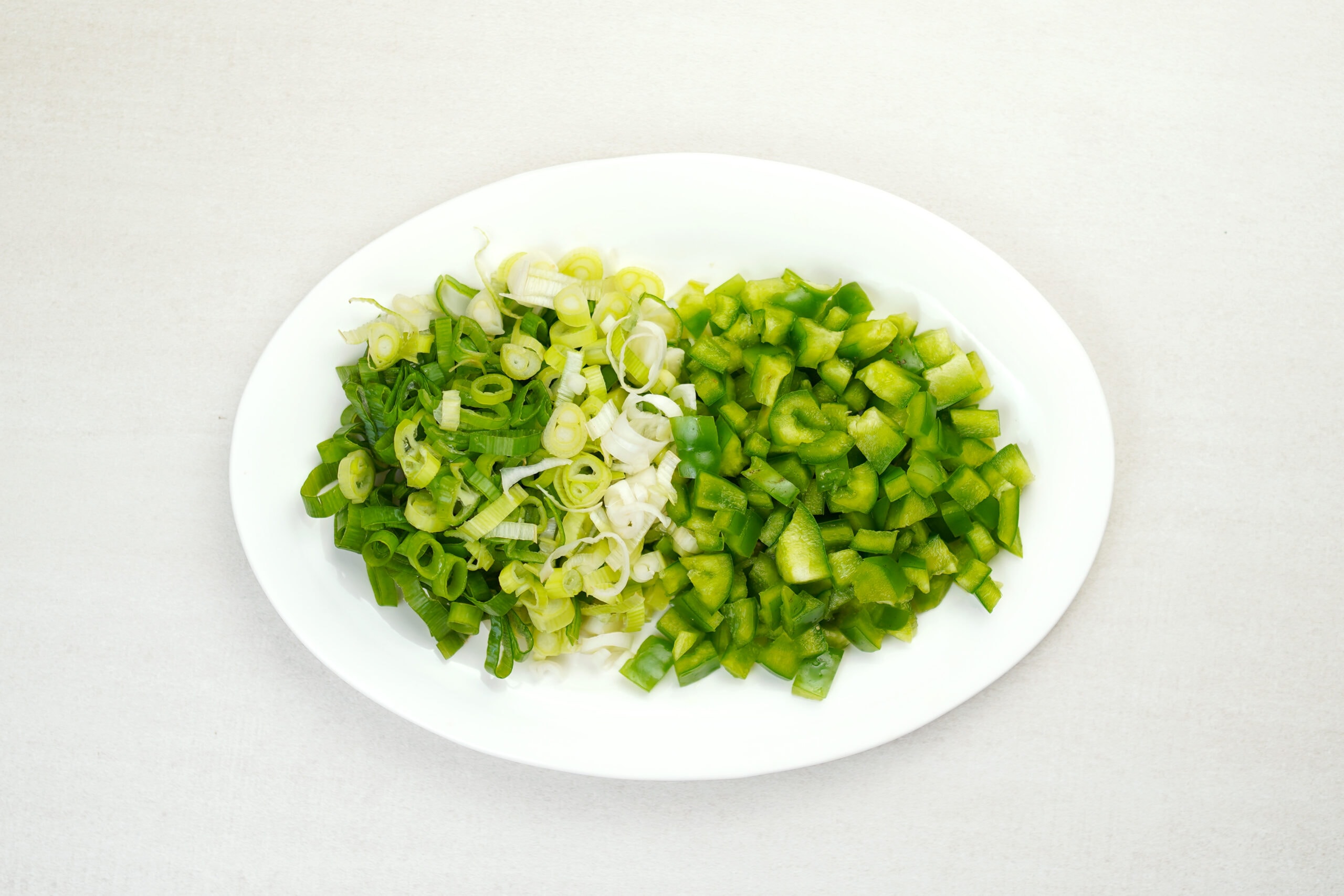 Chopped green onions and bell peppers on white plate